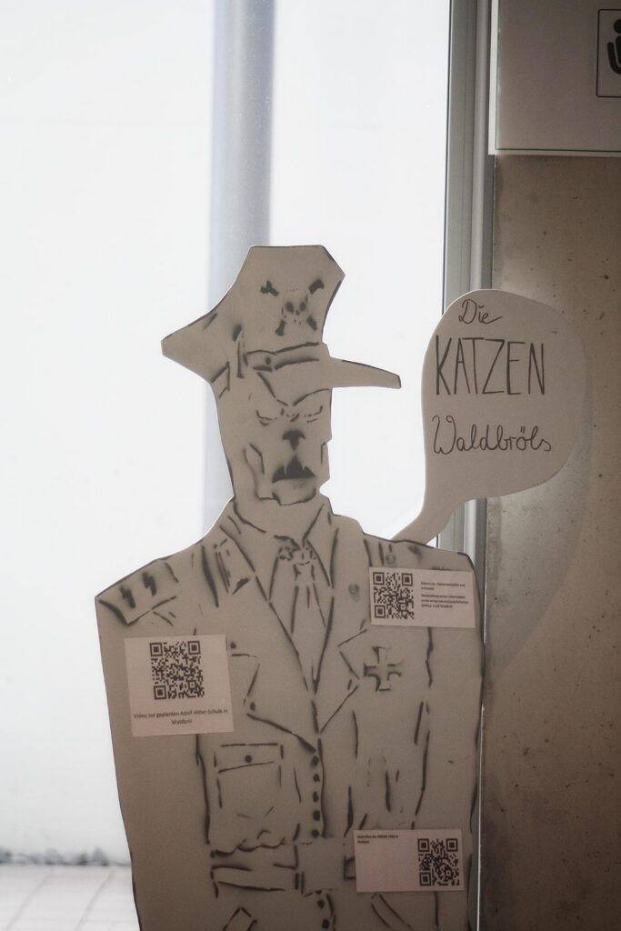 Pappaufsteller eines Polizeibeamten mit Sprechblase und QR-Codes.