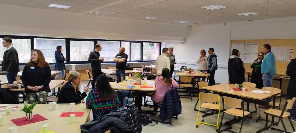 Gruppendiskussion in einem hellen Klassenraum mit Tischen und Stühlen.