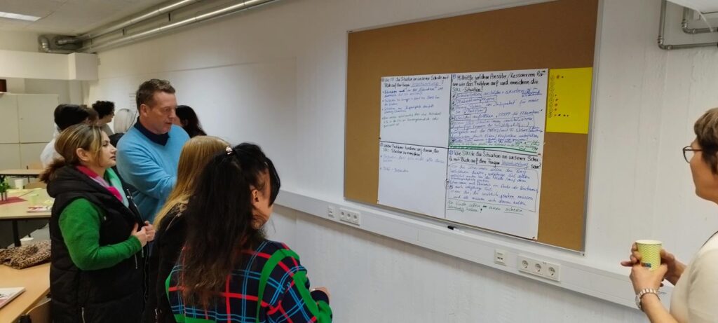 Gruppen von Personen stehen vor einer Wand mit Notizen und Skizzen.