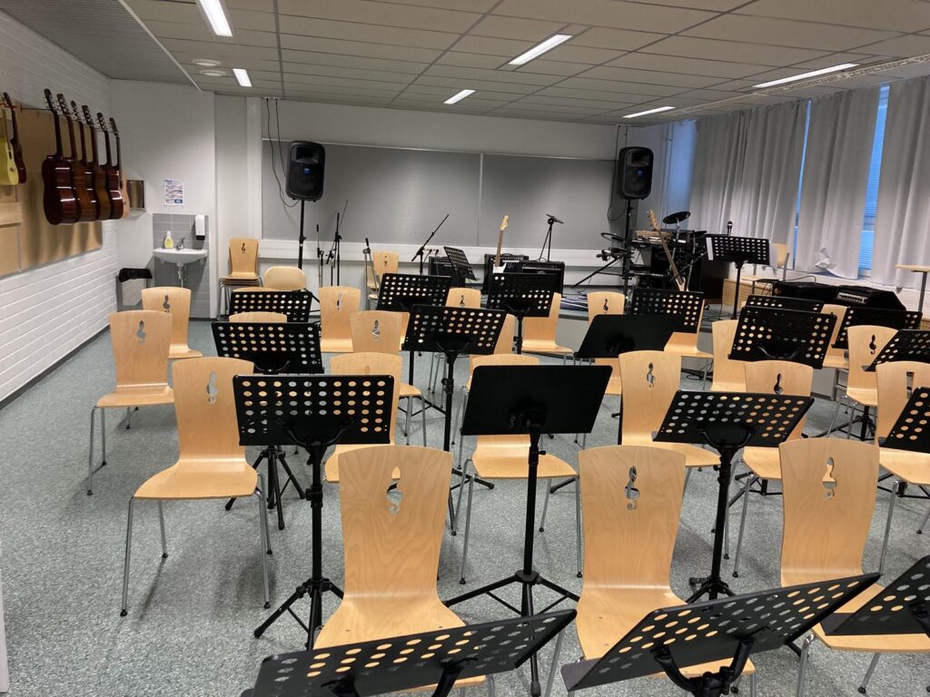Ein Probenraum mit leeren Stühlen und Notenständern.