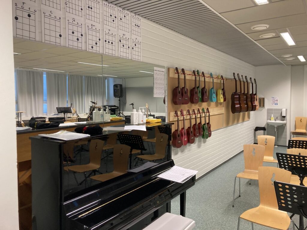 Ein Musikraum mit einem Klavier, Gitarren an der Wand und Notenblättern.