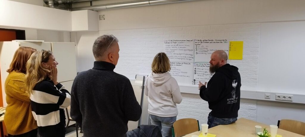 Gruppe von Personen betrachtet eine Präsentation an einer Wand.