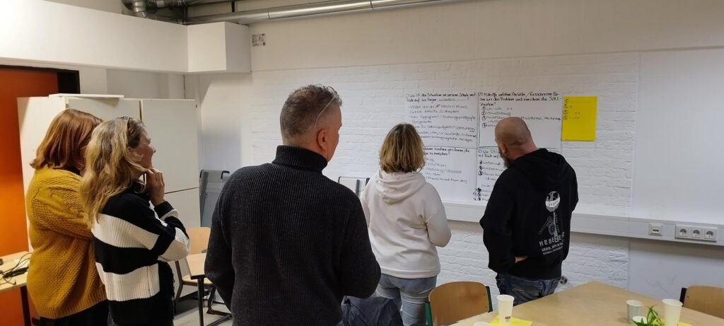 Personen stehen vor einer Wand mit Notizen in einem Raum.