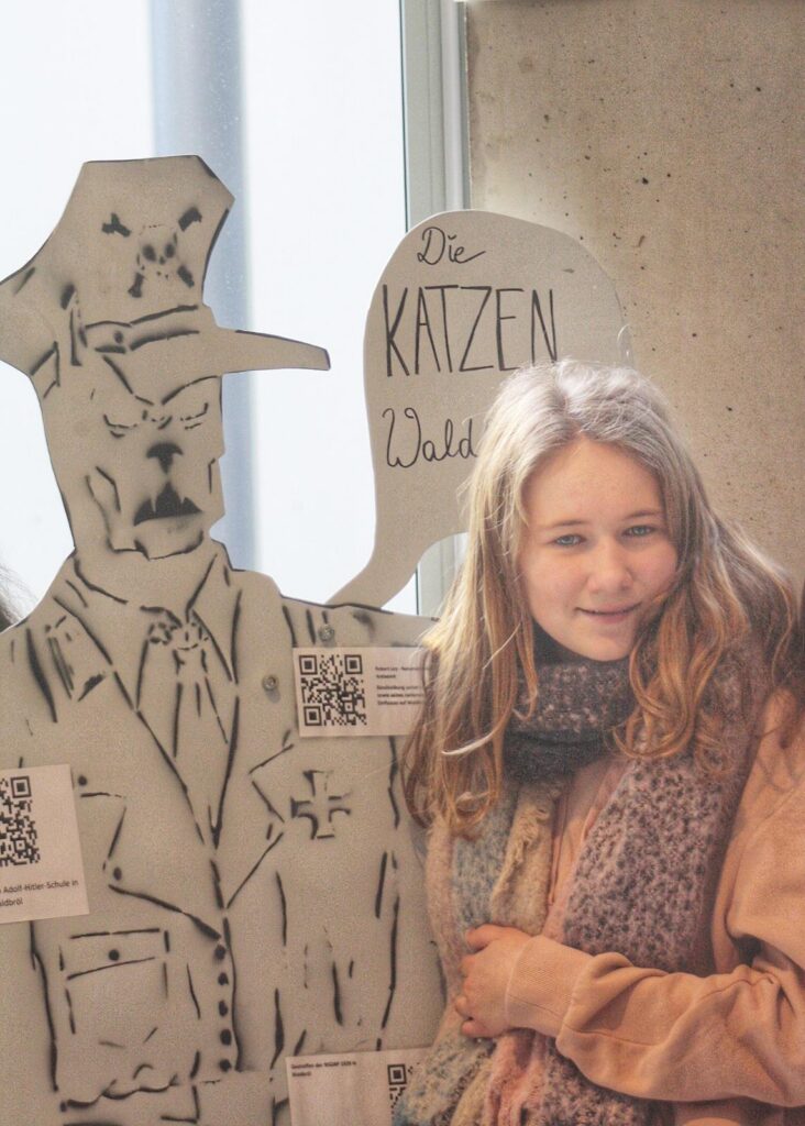 Mädchen steht neben einem lebensgroßen Aufsteller eines Polizisten.