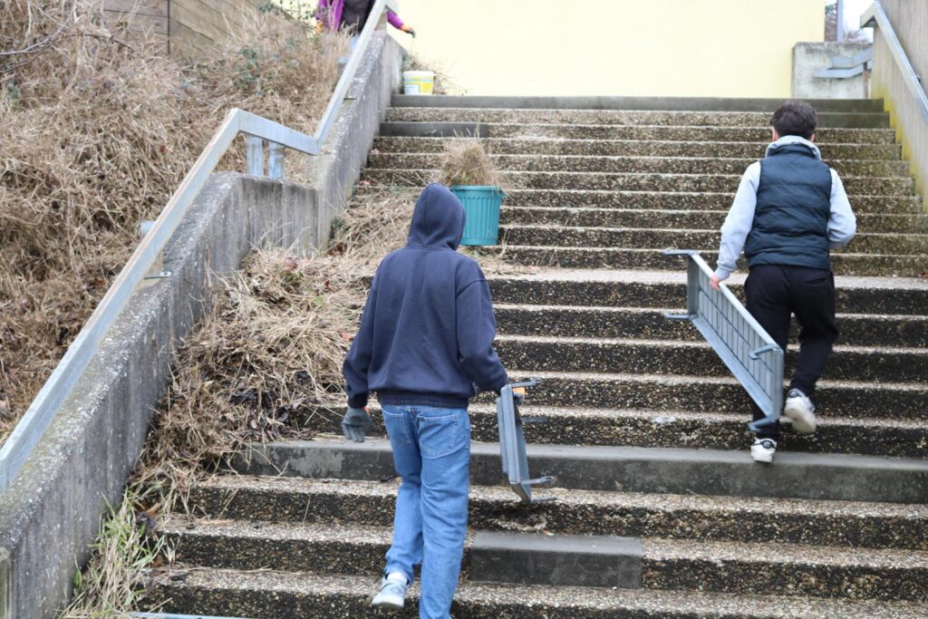 Zwei Personen tragen Gegenstände die Treppe hinauf.