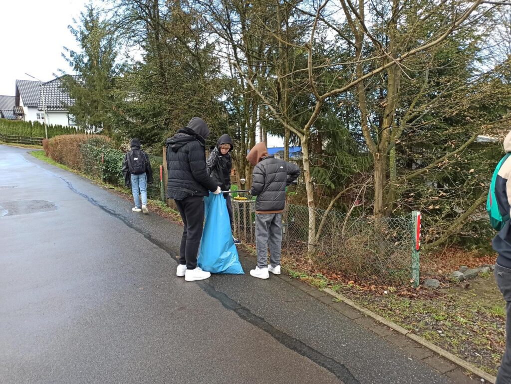 Personen sammeln Müll am Straßenrand in einer Wohngegend.