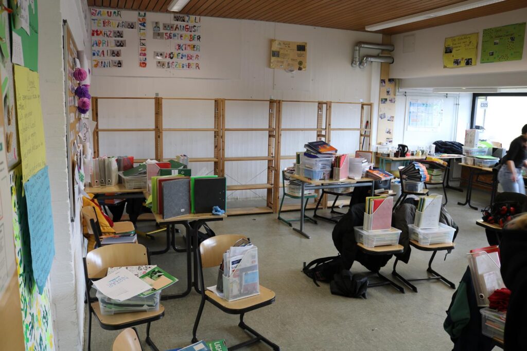 Klassenzimmer mit Tischen, Stühlen und Lernmaterialien.