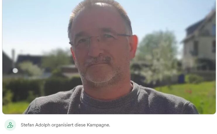 Portrait eines Mannes mit Brille, hinter ihm ein verschwommener Garten.