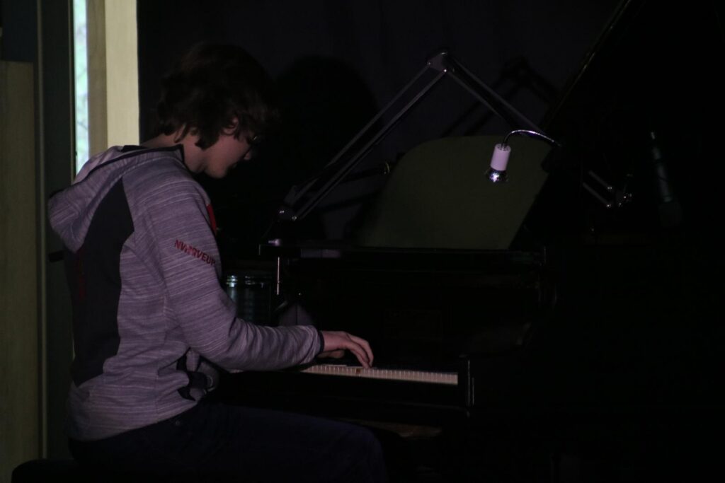 Ein Schüler spielt Klavier in einem dunklen Raum.