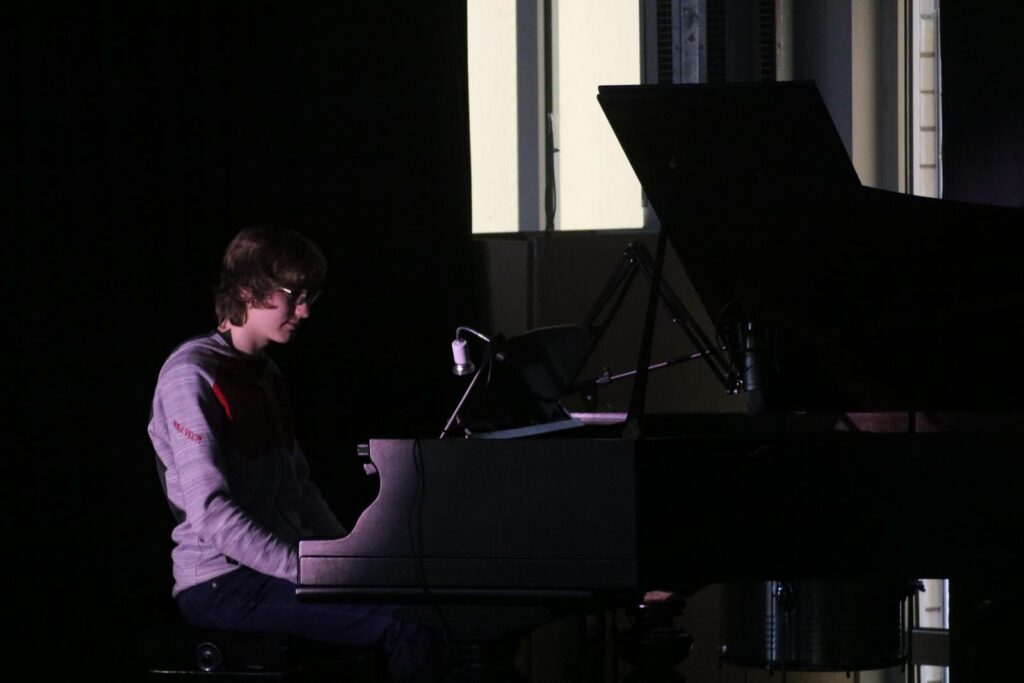 Junger Mann sitzt am Klavier und spielt in gedämpfter Beleuchtung.