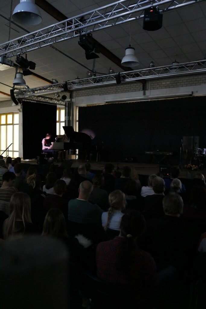 Ein Konzertsaal mit Publikum, ein Pianist spielt auf der Bühne.