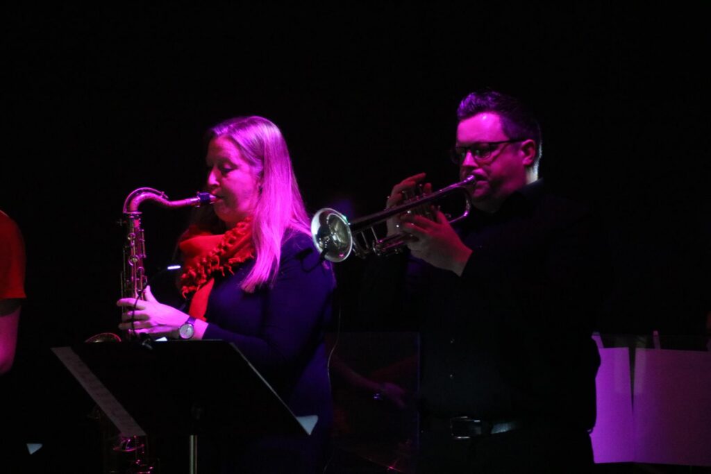 Musiker spielen Saxophon und Trompete auf der Bühne.