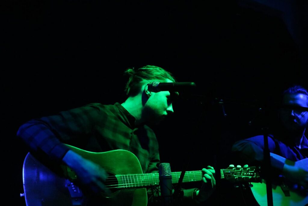 Musiker spielt Gitarre auf der Bühne, beleuchtet von grünem Licht.