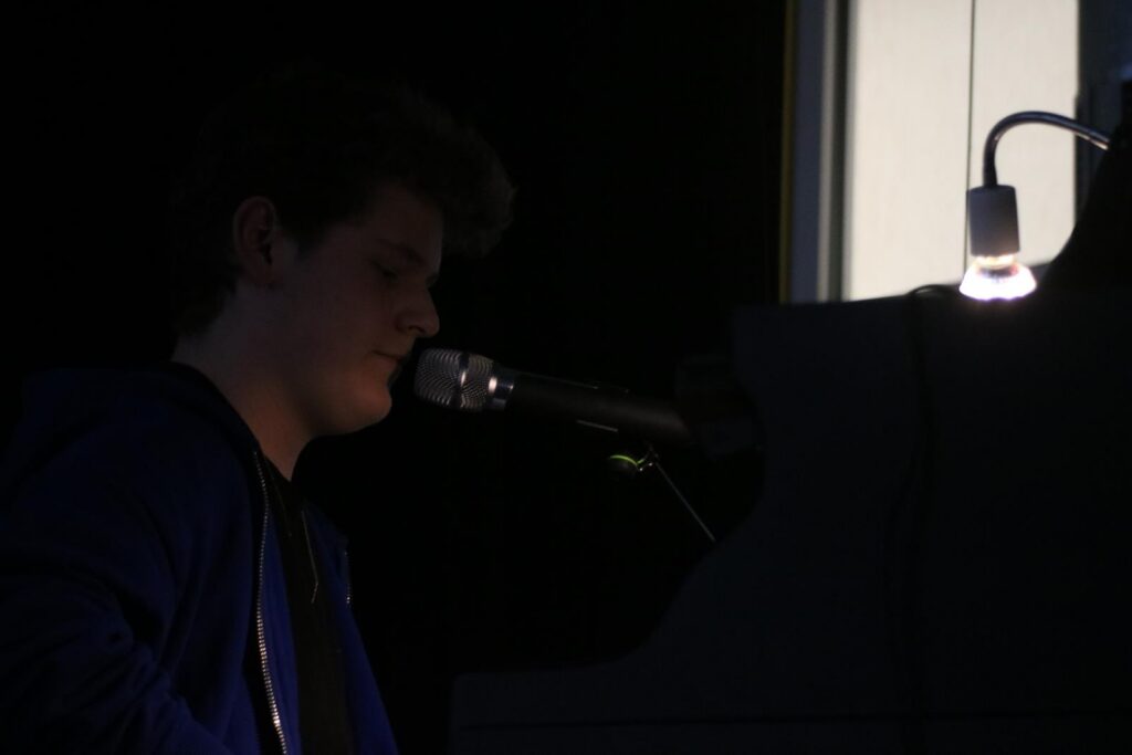 Junger Musiker spielt am Klavier und singt ins Mikrofon.