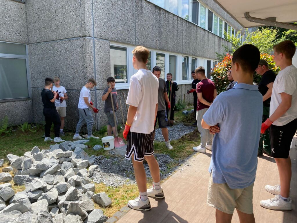 Schüler arbeiten im Freien und helfen beim Gartenprojekt der Schule.