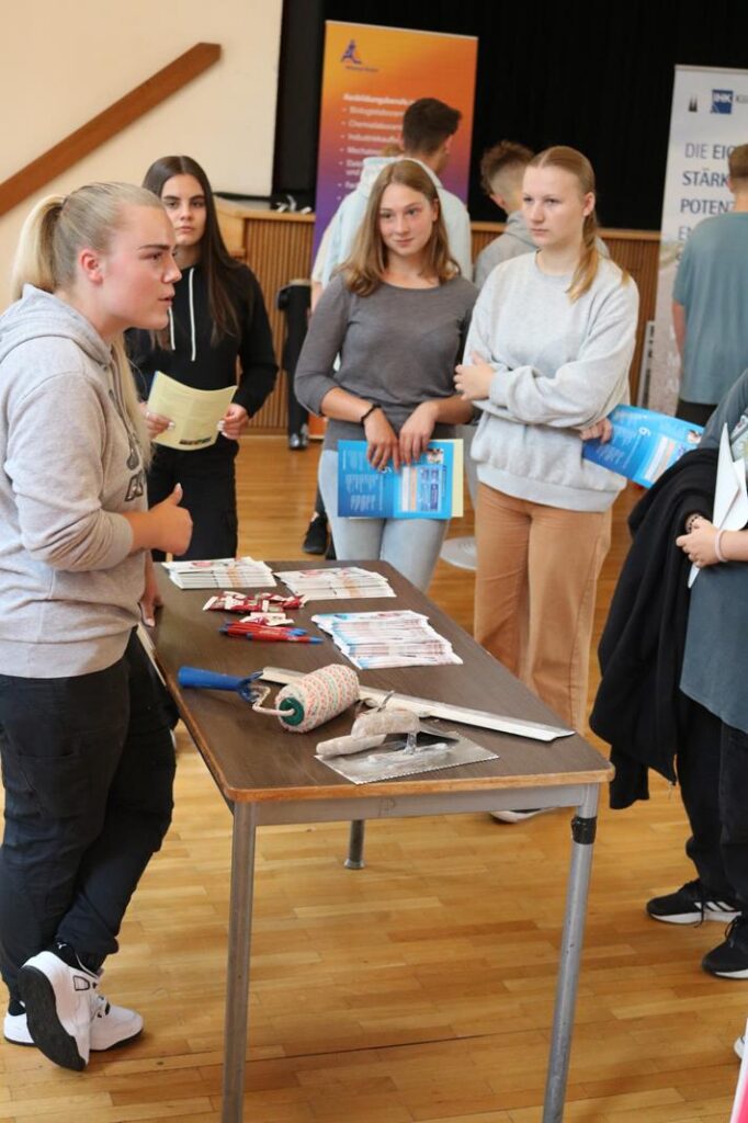 Schülerinnen und Schüler diskutieren an einem Tisch mit Materialien und Prospekten.