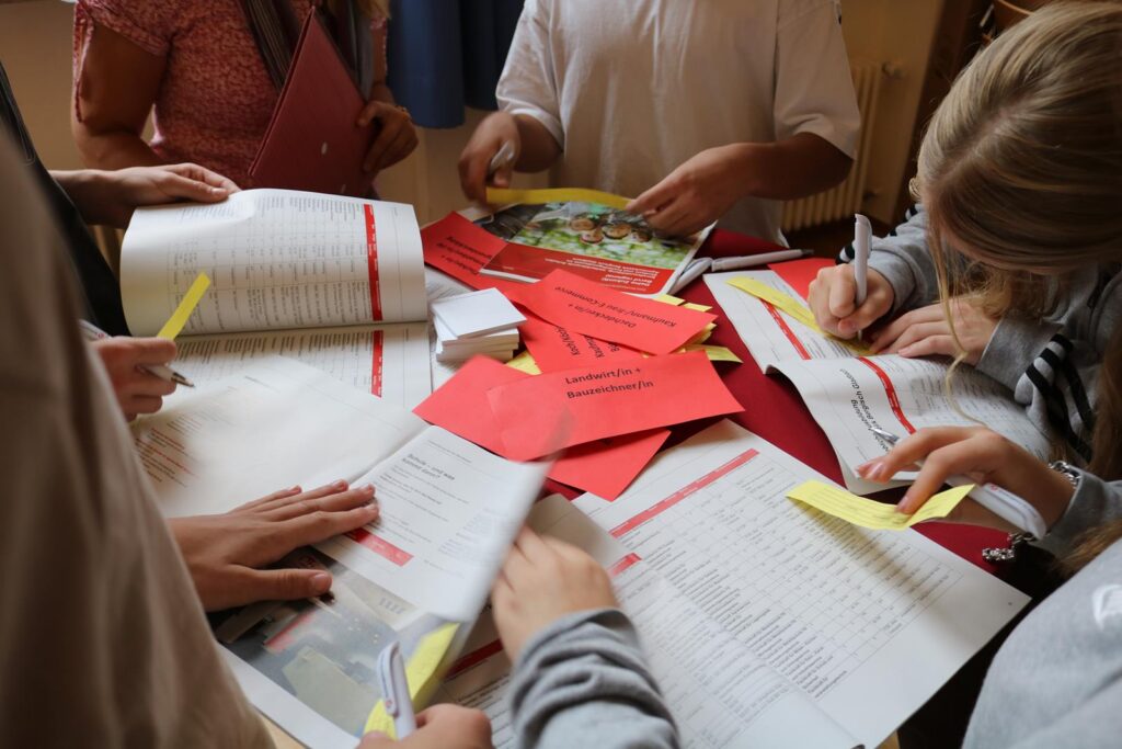 Schüler arbeiten an einem Tisch mit Heften und Notizen.