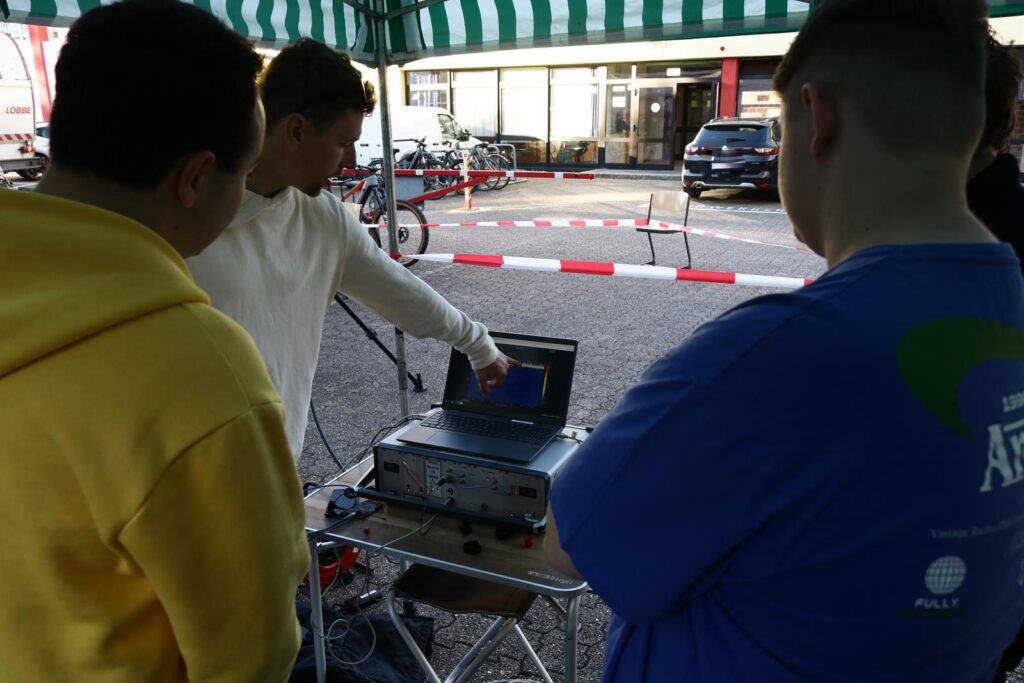 Junge Menschen schauen einem Präsentierenden an einem Laptop zu.
