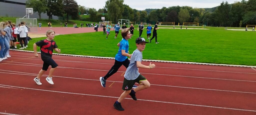 Schülerinnen und Schüler laufen auf einer Sportbahn bei einem Wettkampf.