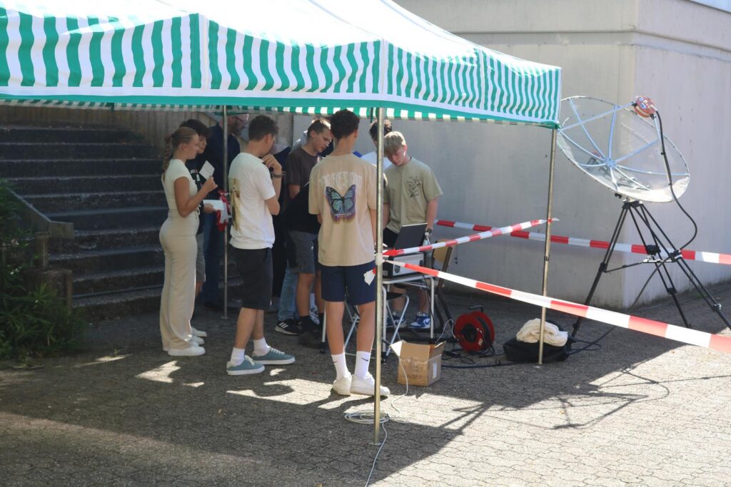 Gruppe von Schülern unter einem Zeltdach bei einer Veranstaltung.