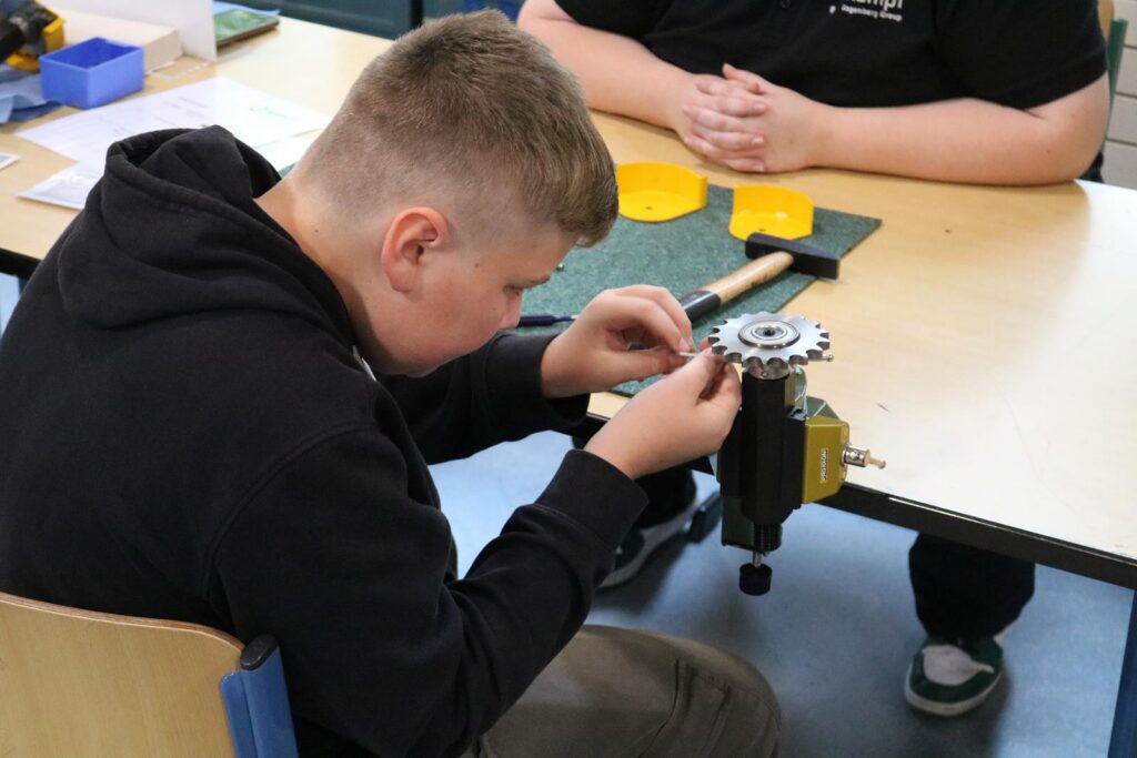 Schüler arbeitet an einem Zahnradsatz am Tisch in der Werkstatt.