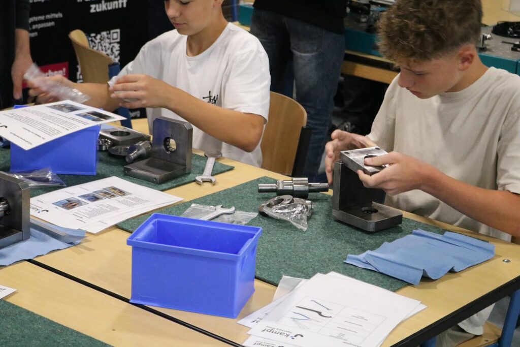 Schüler arbeiten an technischen Projekten an einem Tisch mit Materialien.