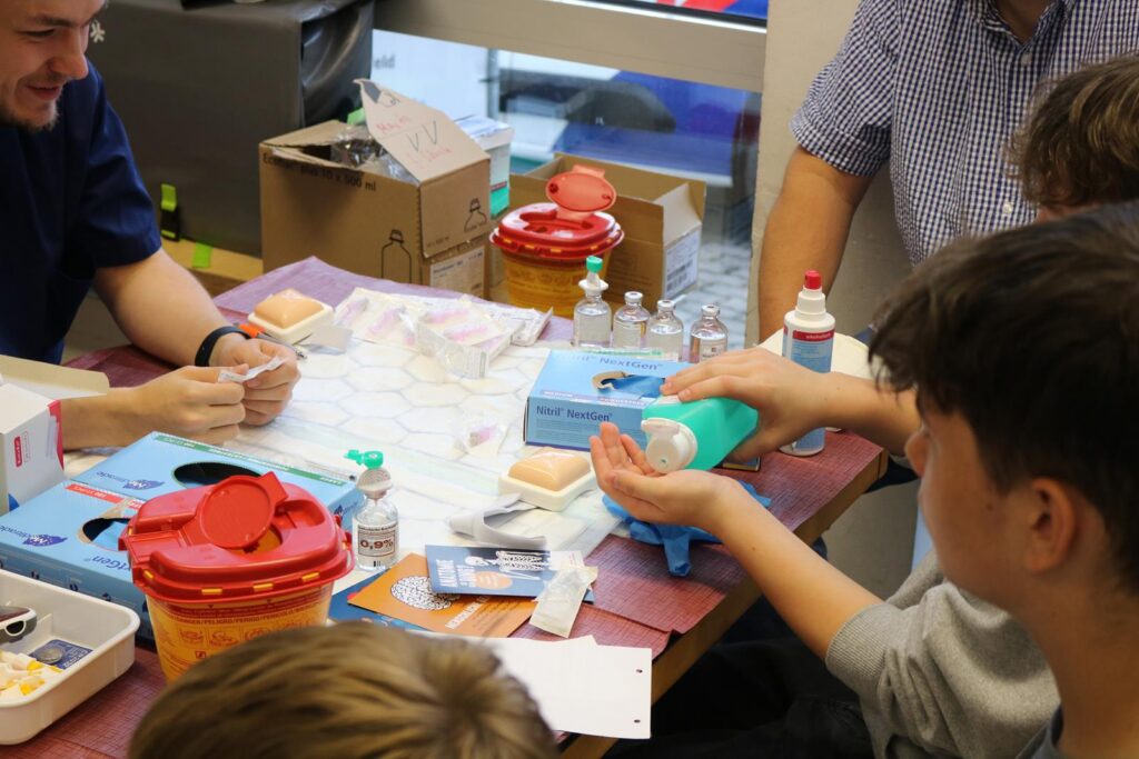 Schüler arbeiten an einem Tisch mit medizinischen Materialien und Utensilien.