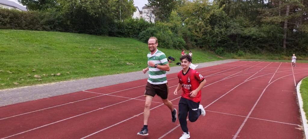 Ein Erwachsener und ein Kind laufen auf einer Laufbahn.