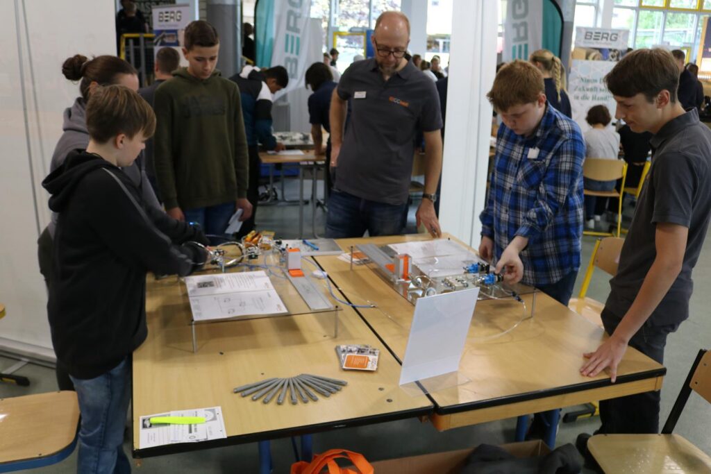 Gruppenschüler arbeiten an einem Experiment an einem Tisch. Ein Lehrer beobachtet.