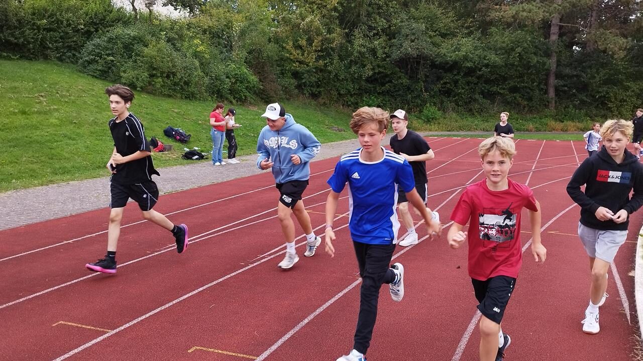 Schülerinnen und Schüler laufen auf einer Tartanbahn.