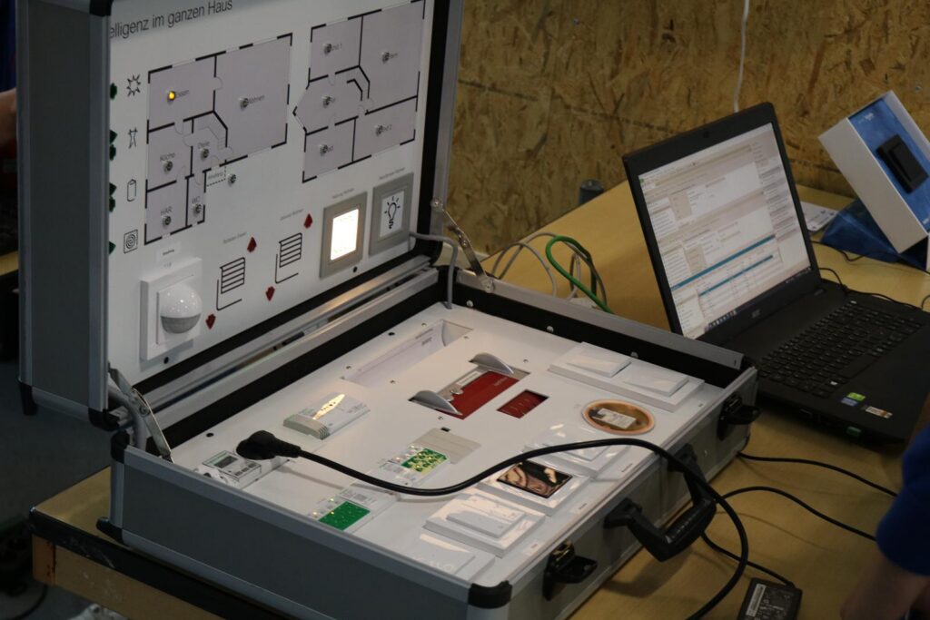 Ein geöffneter Koffer mit elektronischen Schaltkreisen und einem Laptop daneben.
