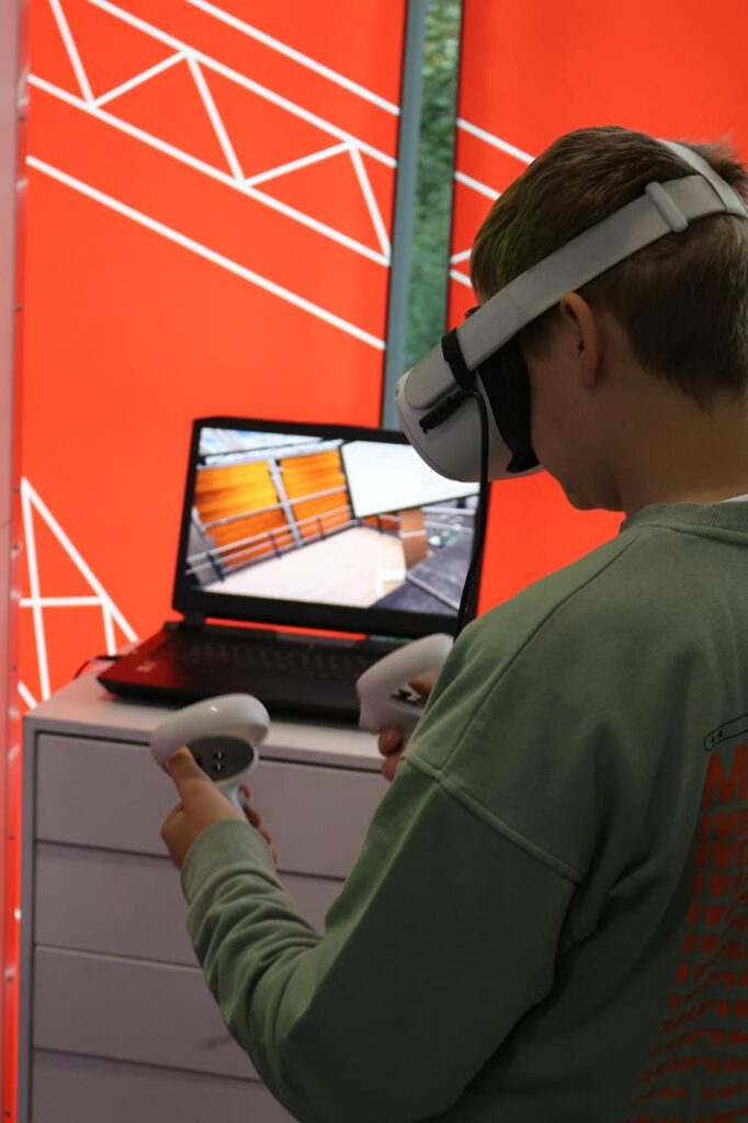 Schüler mit VR-Brille interagiert mit einem Computerbildschirm.