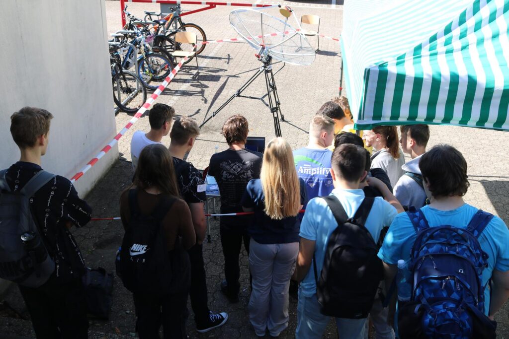 Schüler stehen vor einem abgesperrten Bereich mit Fahrrädern und Ausrüstung.