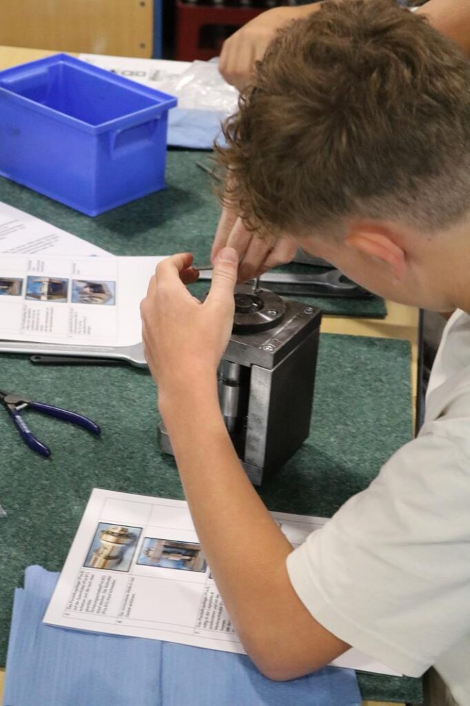 Schüler arbeitet an einem Gerät und studiert dazu Unterlagen.