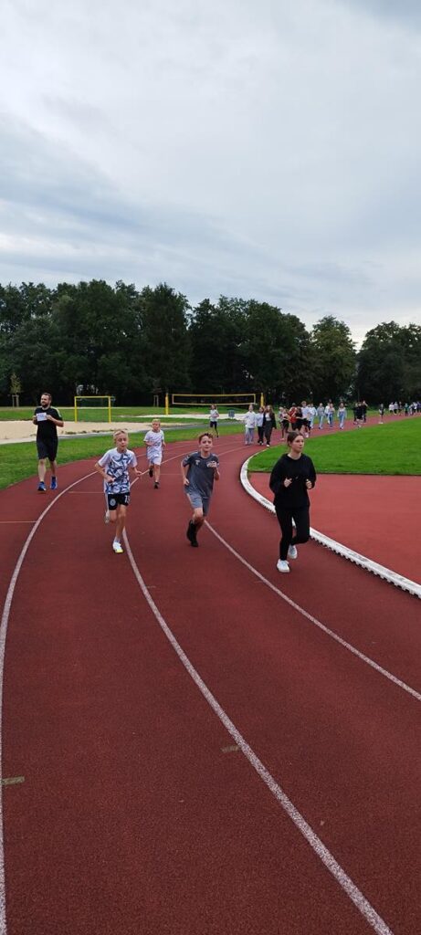 Kinder laufen auf einer Laufbahn während eines Sportevents.