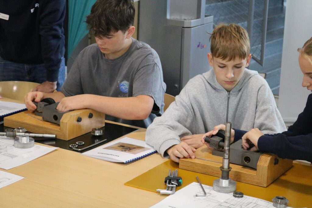 Schüler arbeiten an technischen Bauprojekten an einem Tisch.