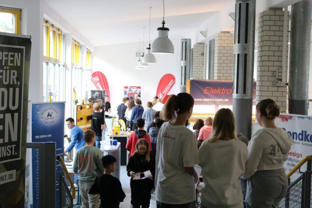 Schülerinnen und Schüler stehen auf einer Treppe und beobachten eine Veranstaltung im Gebäude.