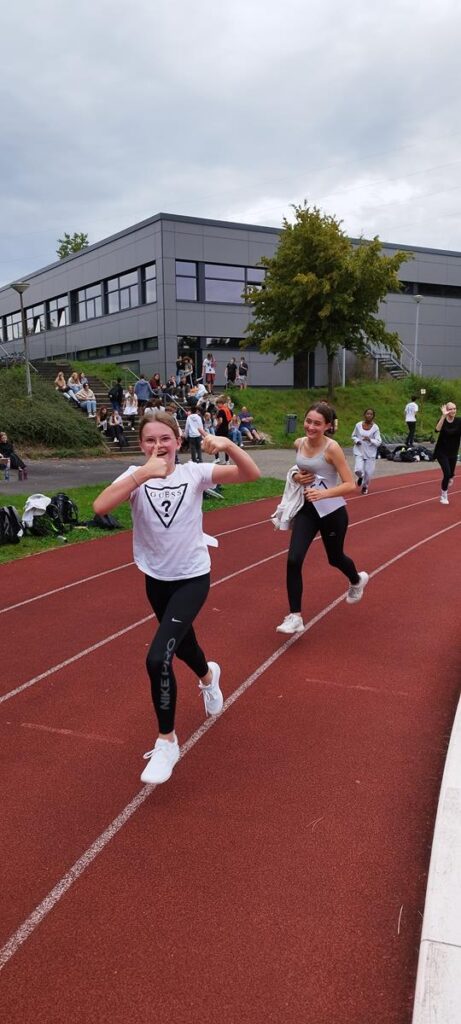 Schülerinnen laufen auf der Laufbahn während eines Sportevents.