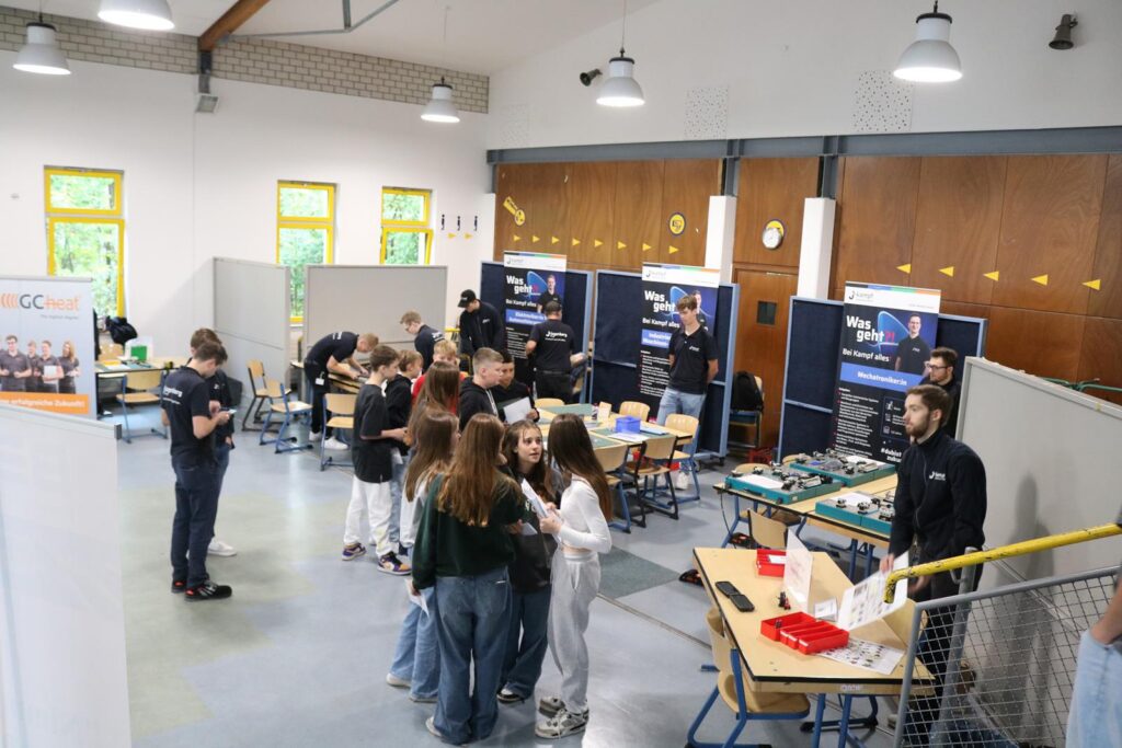Schüler arbeiten an Projekten in einem Klassenraum mit mehreren Tischen und Präsentationen.