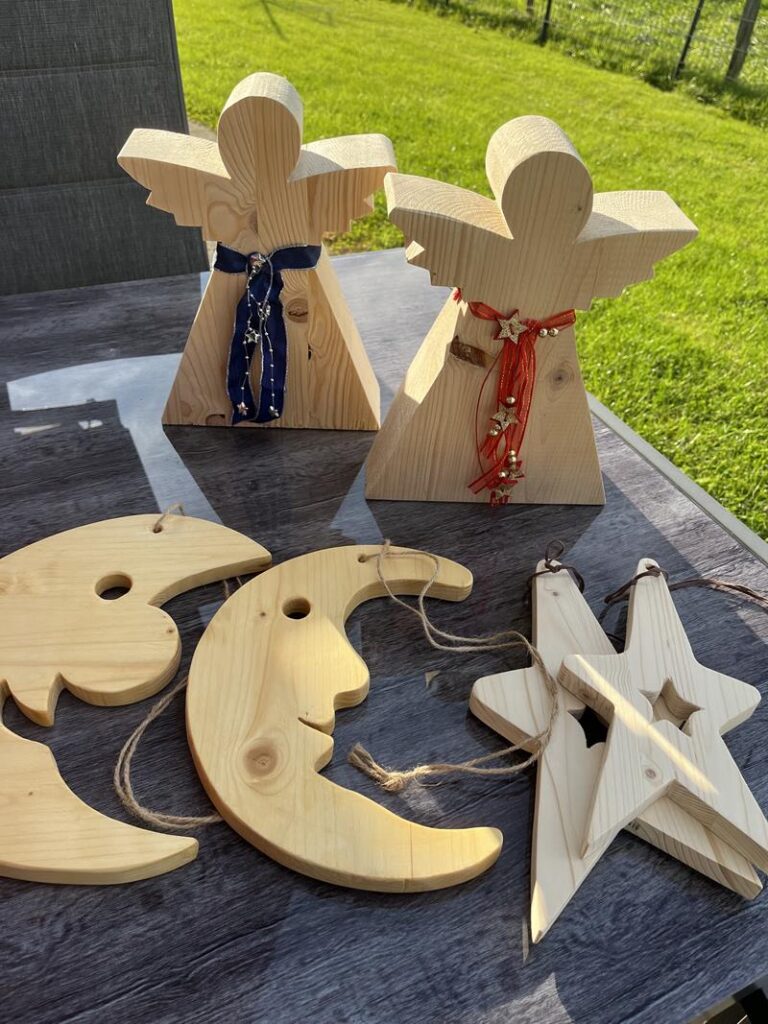 Holzfiguren in Form von Engeln und Mond-Stern-Motiven auf einem Tisch.