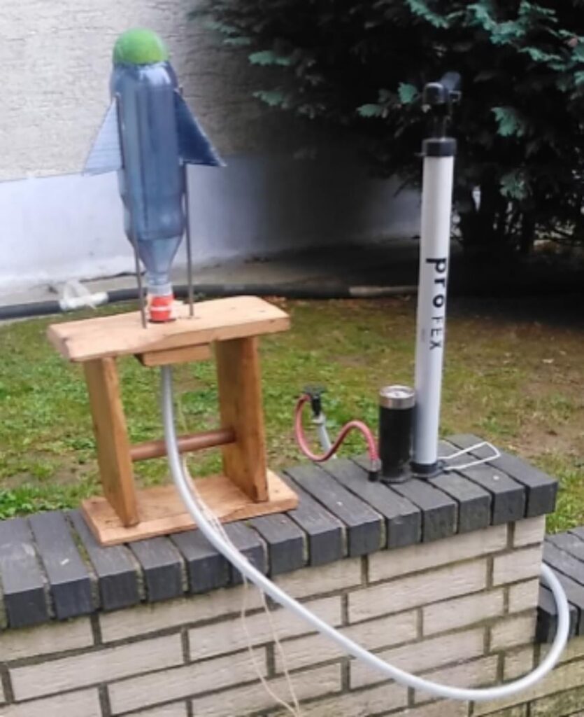 Modellrakete aus einer Plastikflasche und einer Pumpe auf einem Holzgestell.