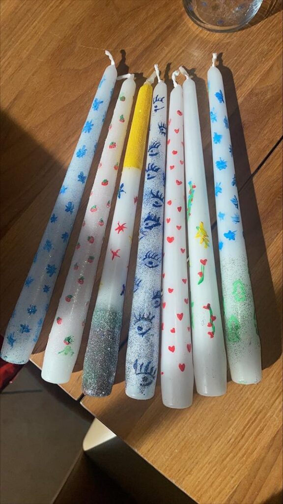 Bunte Kerzen mit verschiedenen Mustern auf einem Holztisch.