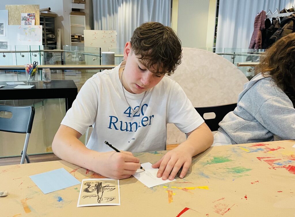 Schüler zeichnet an einem Tisch in einem Kunstraum.