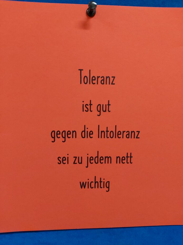 Rotes Plakat mit dem Text über Toleranz und Nettigkeit.