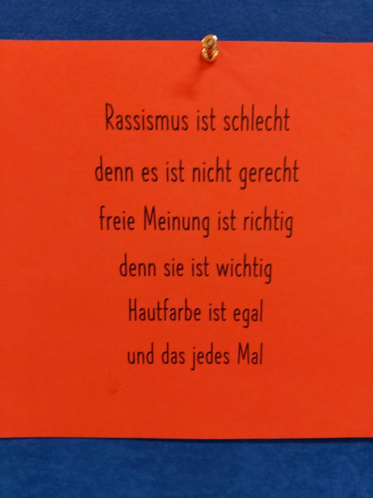 Ein orangefarbener Zettel mit einem Gedicht über Rassismus und freie Meinungsäußerung.