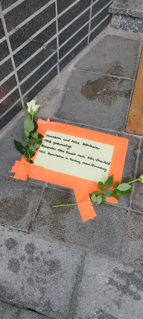Papier mit Botschaft und weißen Rosen auf dem Boden.