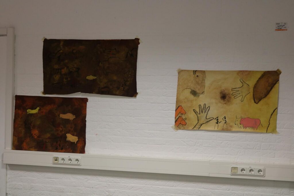 Drei Kunstwerke an einer Wand, zwei dunkle und ein helles Bild.