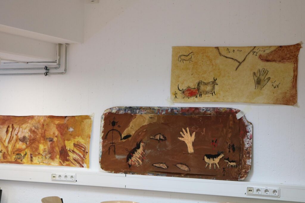 Höhlenmalereien an einer Wand, Kunstwerke aus verschiedenen Farben und Formen.