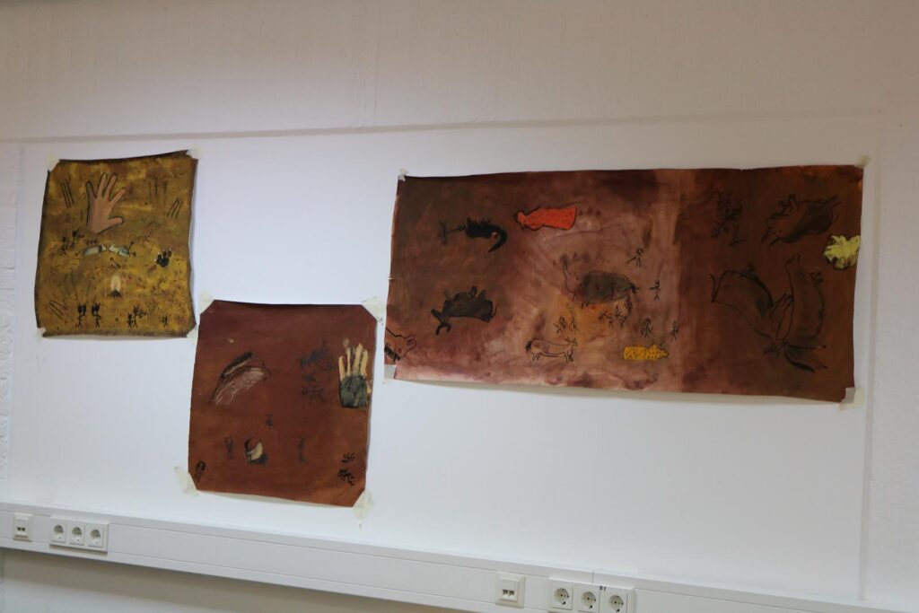Drei gemalte Bilder an einer Wand, mit verschiedenen Tierdarstellungen.
