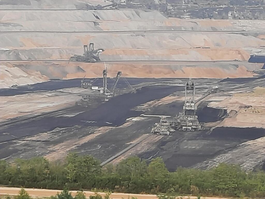 Tagebau mit Fördermaschinen und schwarz-gelber Erde im Hintergrund.
